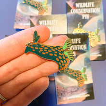 Load image into Gallery viewer, Nembrotha Nudibranch Conservation Pin Closeup with Hand
